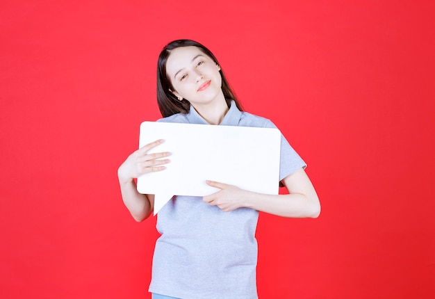 Joyful young woman holding board and looking at front 