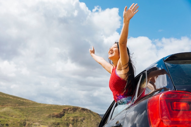 Joyful young woman raising hands to sky