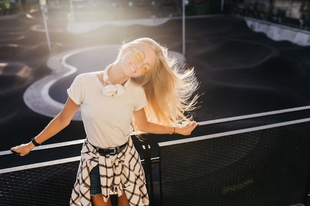 Joyful young woman spending sunny day in skate park.