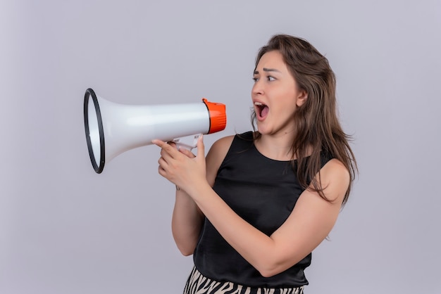 Free photo joyful young woman wearing black undershirt speaks through loudspeakers on white wall