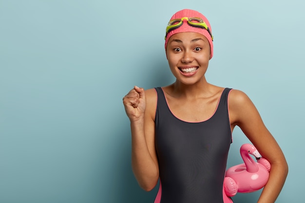 Joyous female swimmer posing with goggles