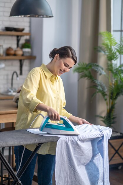 Joyous woman ironing wrinkled clothes on the ironing-board