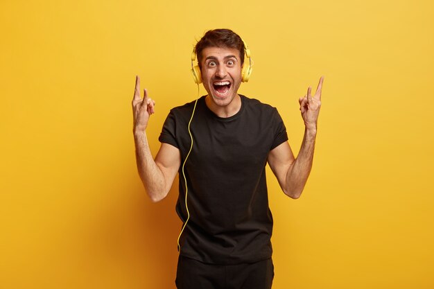 Joyous young hipster listens rock music in stereo headphones