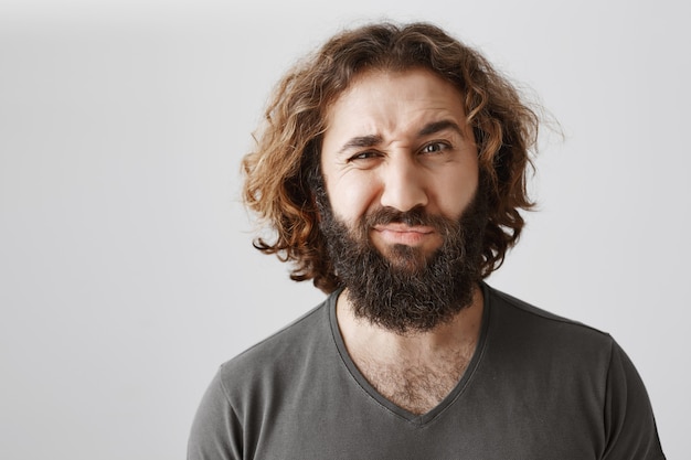 Judgemental middle-eastern man grimacing unsure, having doubts and being displeased