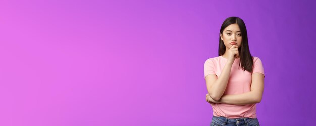 真剣な表情のスマートなアジアの女の子は、専門家の顔に触れて、思慮深く目を細めます。