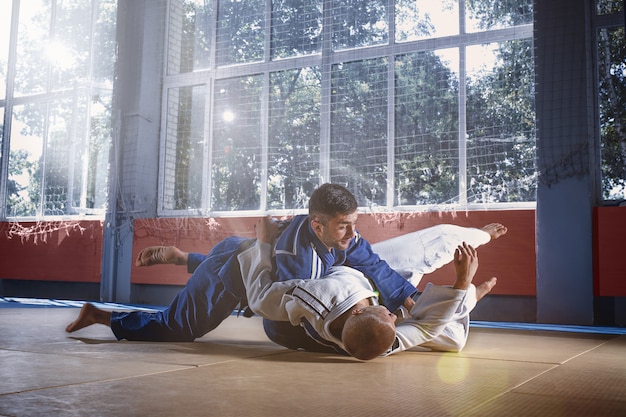 Foto gratuita combattenti di judo che mostrano abilità tecniche mentre praticano arti marziali in un club di combattimento