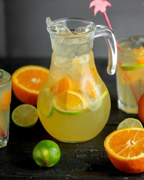 A jug of citrus beverage with orange and lime slices