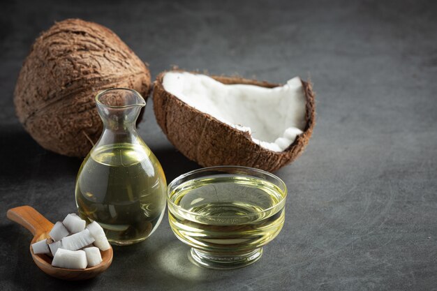 Jug of coconut oil whit coconut put on dark background Free Photo