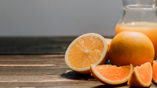 Brocca di delizioso succo d'arancia circondato da arance con spazio di copia