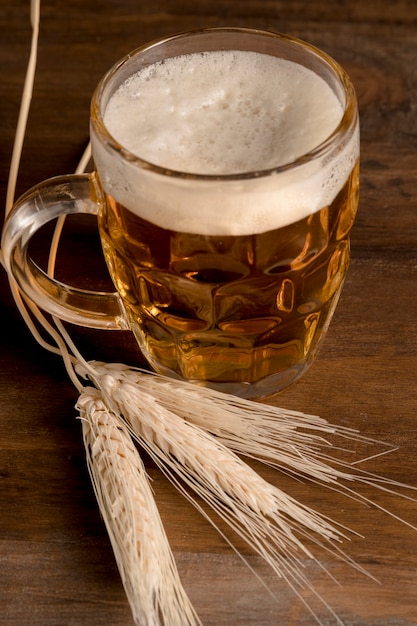 Jug of fresh beer with spike barley on wooden table 