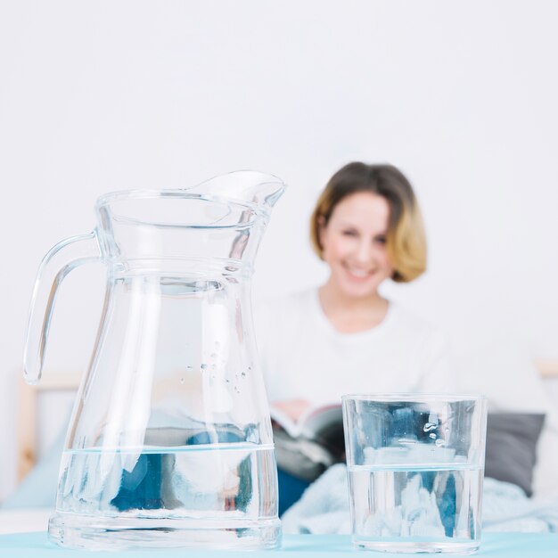 Jug and glass near reading woman