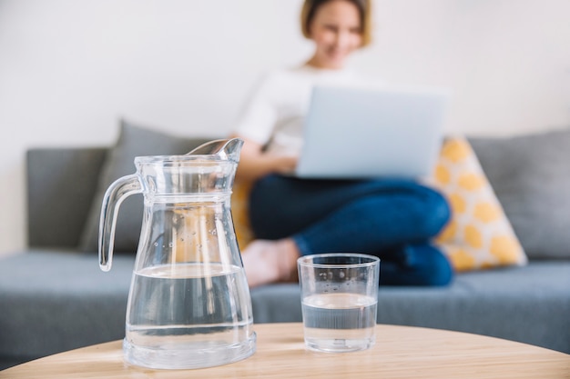 Jug and glass of water near woman