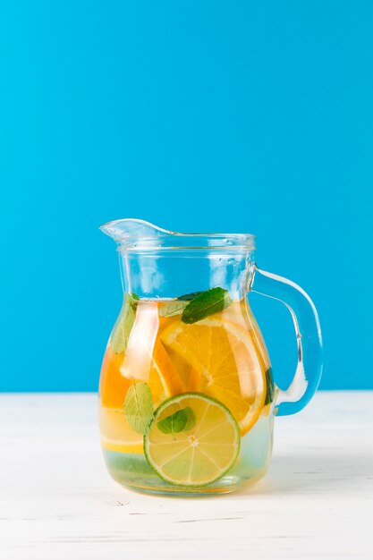 Jug with homemade lemonade with blue background