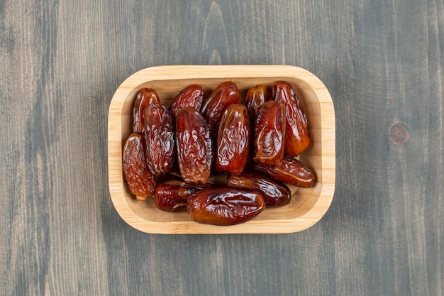 Juicy dates in a wooden plate on a wooden table . High quality photo