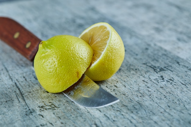 Juicy half cut yellow lemon on marble surface with knife