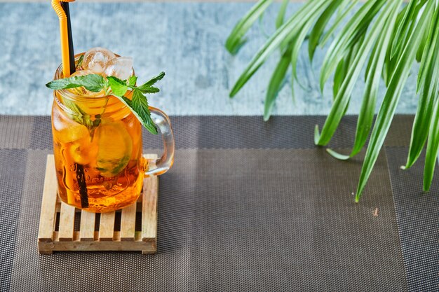 Juicy lemonade with straw and mint on the plant surface 