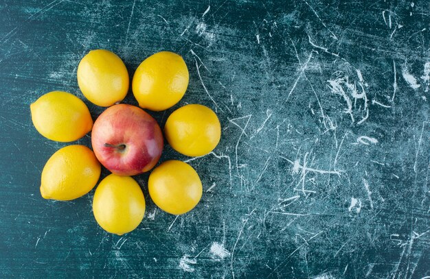 Juicy lemons and red apple on marble table. 