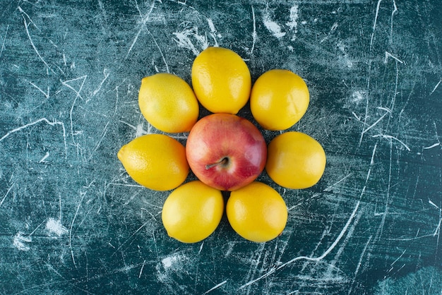 Limoni succosi e mela rossa sulla tavola di marmo.