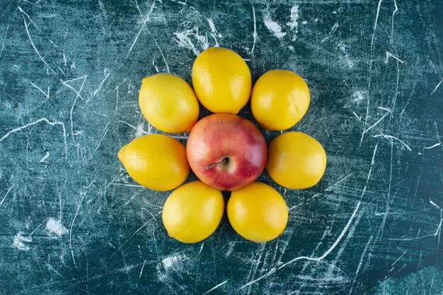 Juicy lemons and red apple on marble table. 