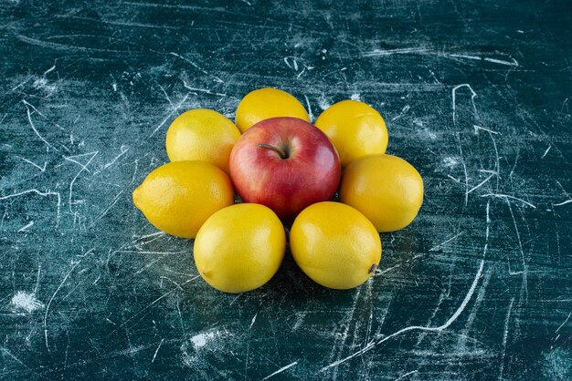 Foto gratuita limoni succosi e mela rossa sulla tavola di marmo.