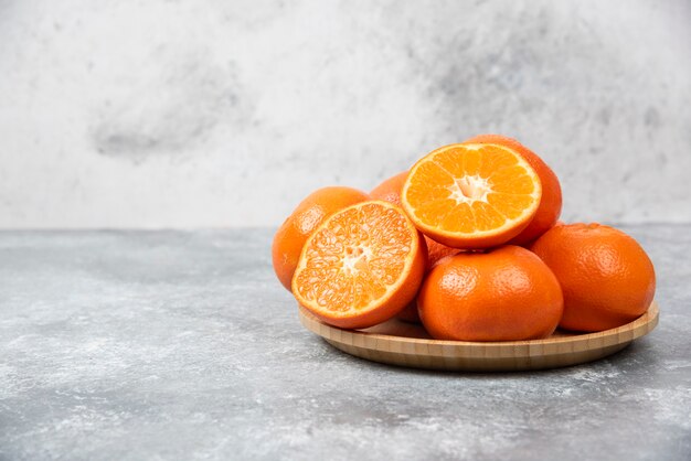 石のテーブルの上の木の板のスライスとジューシーなオレンジ色の果物。