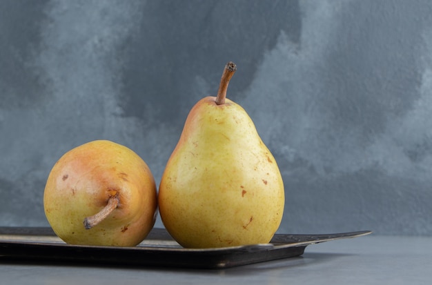 Juicy pears on an ornate tray on marble 