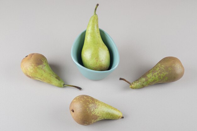 Juicy pears in and next to a tiny bowl on marble 