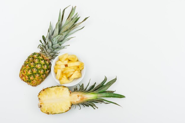 Juicy pineapple half and slices on white, flat lay.