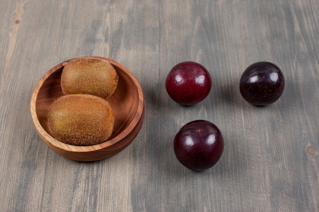 Juicy plums with kiwi on a wooden table. High quality photo