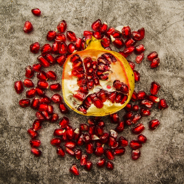 Juicy pomegranate fruit with seeds against weathered background