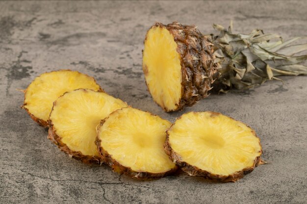 Juicy ripe pineapple with its crown placed on stone surface.