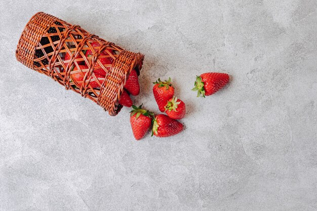 Juicy strawberries poured out chaotically on a concrete light wall. delicious fruits in summer season. natural products and natural resources.