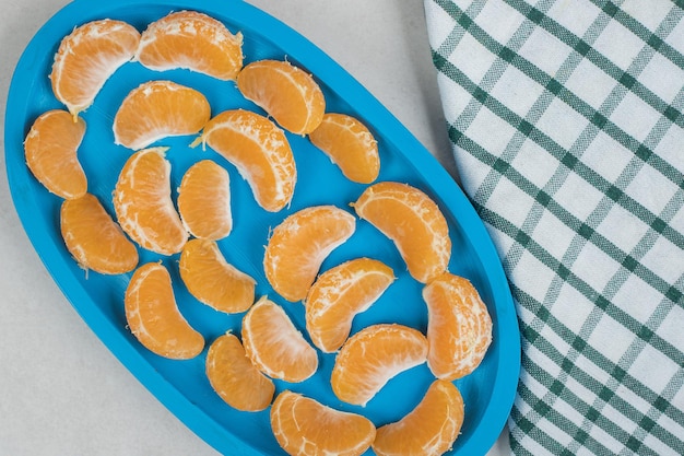 Сочные дольки мандарина на синей тарелке