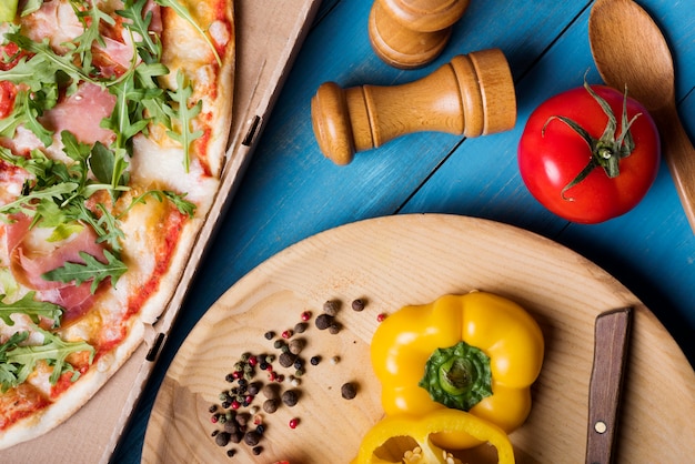 Juicy vegetables and spices with bacon pizza on blue textured background