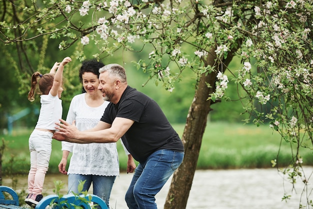 Jump at me. Cheerful couple enjoying nice weekend outdoors with granddaughter. Good spring weather