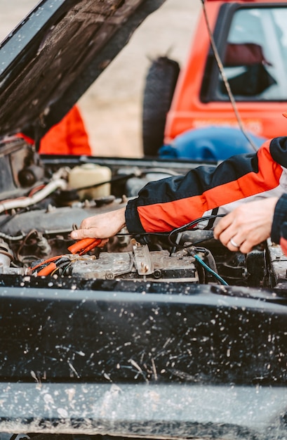 Free photo jump-starting the dead battery using jumper electrical wires.