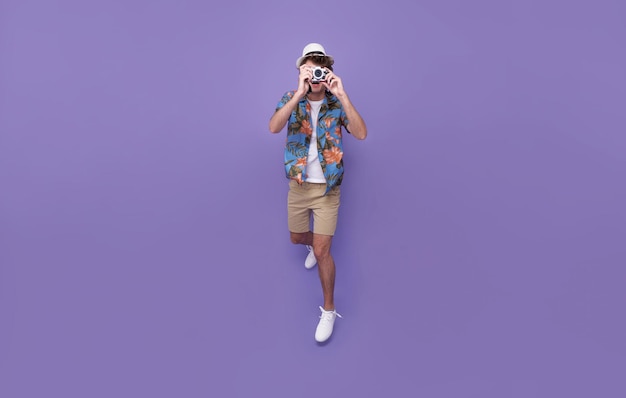 Прыгающий фотограф мужчина фотографирует фото с камерой dslr на изолированном студийном фиолетовом фоне