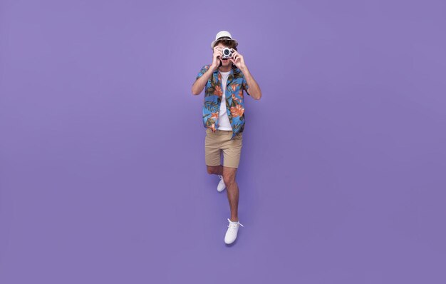 Jumping photographer man is taking images photo with dslr camera isolated studio purple background