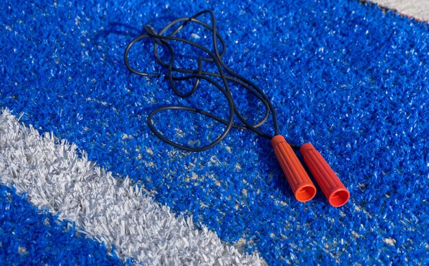 Скакалка лежит на синей земле на открытом воздухе на футбольном поле