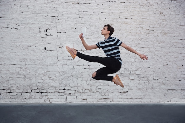 Jumping young buinessman in front of buildings, on the run in jump high