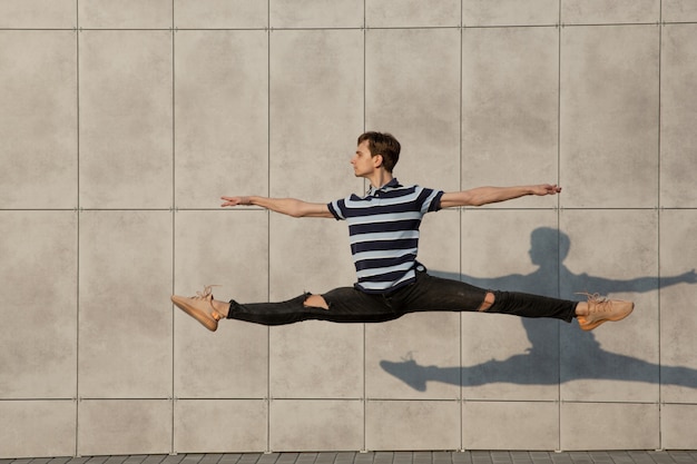 Jumping young buinessman in front of buildings, on the run in jump high