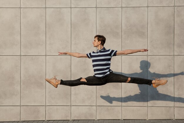 Jumping young buinessman in front of buildings, on the run in jump high