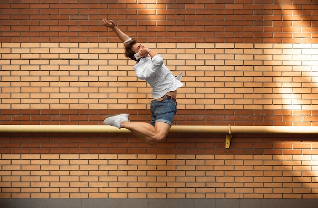 Jumping young buinessman in front of buildings, on the run in jump high