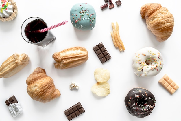 Junk food with chocolate bar and cold drink isolated over white surface