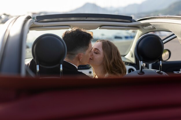 Just married couple kissing inside little car