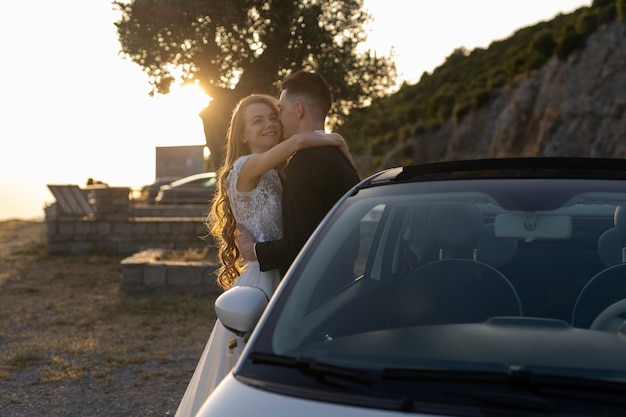 Just married couple next to little car