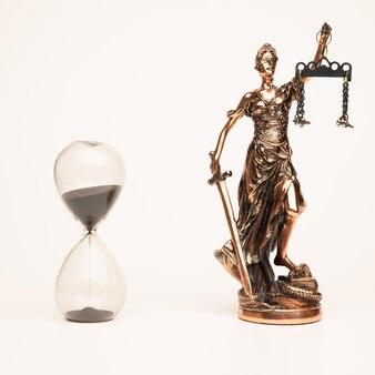 Статуя юстилии или фемиды (символ правосудия) и песочные часы, изолированные на белом фоне с обтравочным контуром