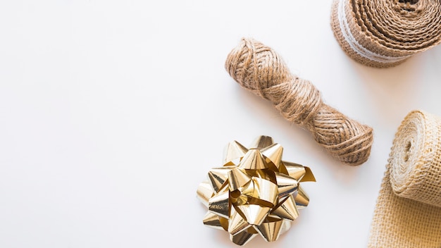 Jute string; golden bow and rolled up weaving ribbon on white background