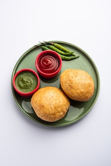 Kachori is a flat spicy snack from india also spelled as kachauri and kachodi. served with tomato ketchup. selective focus