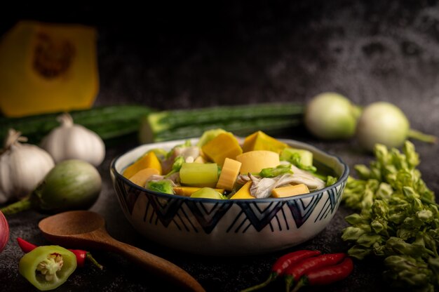 Kaeng Liang in a bowl with spices on a black cement floor.